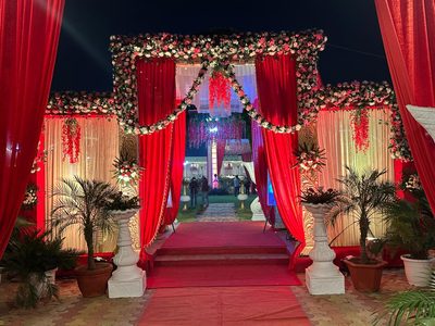 Grand floral entrance gate with red drapes and red carpet at Dharam Vatika, Sohna Gurgaon