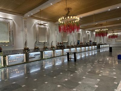 Buffet hall with marble floor and hanging floral chandeliers at Dharam Vatika, Sohna Gurgaon